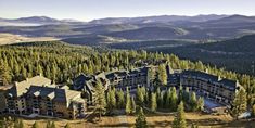 an aerial view of a resort surrounded by mountains and pine trees in the foreground