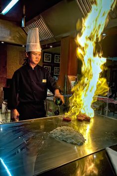 a chef is pouring hot sauce on a piece of food with flames coming out of it