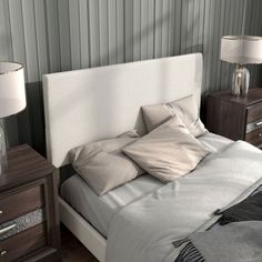 a bed sitting next to two nightstands with lamps on top of them and a white headboard