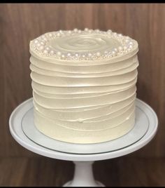 a white cake sitting on top of a plate covered in frosted icing and pearls