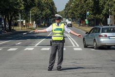 a police officer directing traffic at an intersection on a sunny day with his arms outstretched