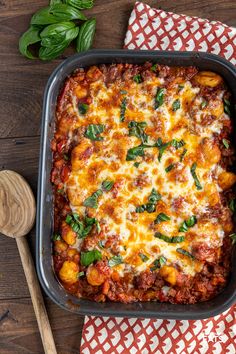 a casserole dish with meat, cheese and spinach on a wooden table