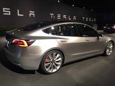 a silver tesla car is on display at an auto show