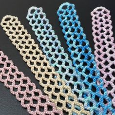 four different colors of crochet on a black surface, one is blue and the other is pink