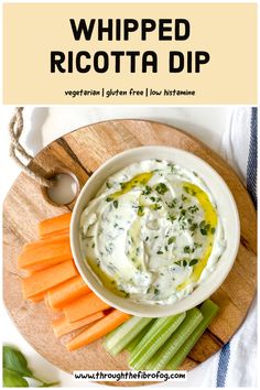 a white bowl filled with dip surrounded by carrots and celery