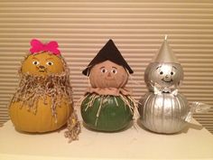 three decorative pumpkins with faces on them sitting on top of a white table next to a striped wall