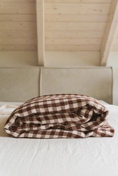 a bed with a brown and white checkered comforter on it's headboard