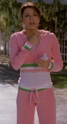 a woman in pink and green tracksuits standing on the street