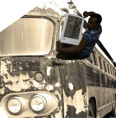 a man sitting on top of an old bus holding a book in his right hand