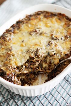 a casserole dish with meat and cheese in it on a striped tablecloth