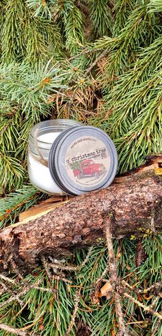 a small tin candle sitting on top of a piece of wood next to a tree branch