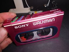 a hand holding a pink sony walkman cassette player