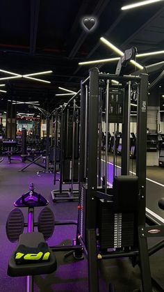 an empty gym with rows of exercise equipment and purple lighting on the ceiling is seen in this image