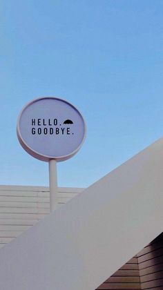 a white sign that says hello goodbye on the side of a building under a blue sky