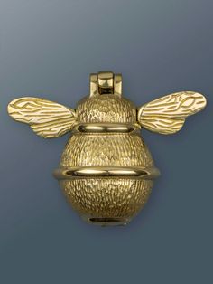 a golden bee shaped object hanging from the ceiling in front of a blue background with an image of a honeybee on it's side