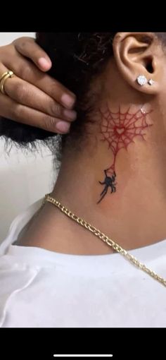 a woman with a spider web tattoo on her neck and behind her ear is a gold chain