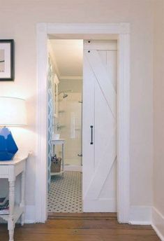 an open door leading to a bedroom with a white table and blue vase on it