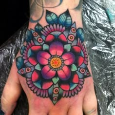 a person's hand with a colorful flower tattoo on the middle of their palm