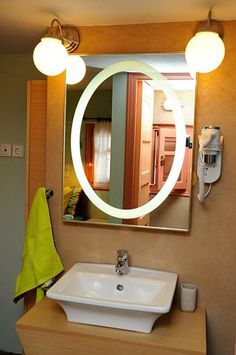 a bathroom sink sitting under a mirror next to a wall mounted hair dryer and towel