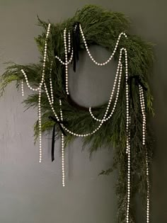 a christmas wreath hanging on the wall next to a potted plant with white lights