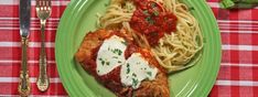 a green plate topped with meat covered in sauce next to pasta on a red and white checkered table cloth