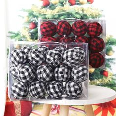 black and white buffalo plaid christmas ornaments in clear plastic boxes on a table next to a christmas tree