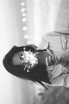 black and white photograph of a woman holding a sparkler in her hand while standing next to a suitcase