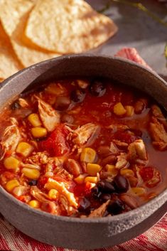 a pot filled with chicken, beans and tortilla chips on top of a table