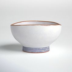 a white bowl with blue stripes on the rim is shown in front of a plain background