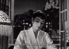 a woman sitting at a table in front of a lamp with the words how to be in the world and of the world