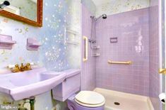 a bathroom with purple walls and flooring next to a white toilet sitting under a mirror