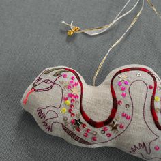 an ornament made out of fabric with beads and thread on the side, sitting on a table