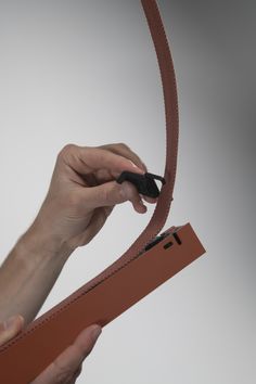 a person is holding a piece of leather with scissors in their hands and pulling it out