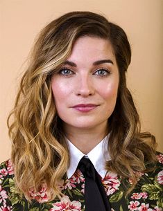 a woman with long hair wearing a floral shirt and tie