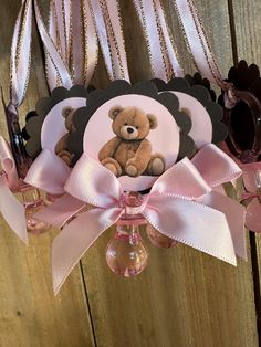 a teddy bear hanging from the side of a wooden wall with pink ribbon and decorations