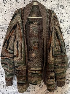 an old sweater hanging on a hanger in front of a wallpapered background