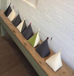 several different colored umbrellas sitting on a wooden bench next to a white brick wall