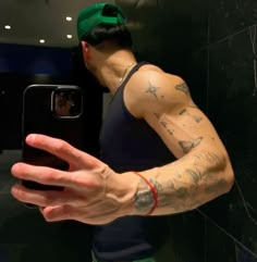 a man with tattoos on his arm taking a selfie in front of a mirror