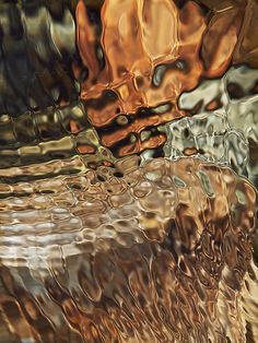 an abstract photograph of water and rocks in brown, green, yellow and orange colors