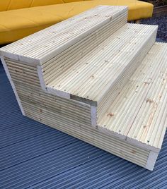 several pieces of wood sitting on top of a blue floor next to a yellow couch