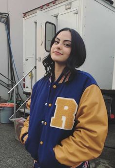 a woman standing in front of a trailer wearing a jacket with the letter f on it