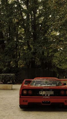 a red sports car parked in front of some trees