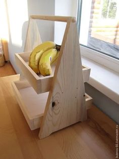 some bananas are sitting in a wooden box on the floor next to a windowsill