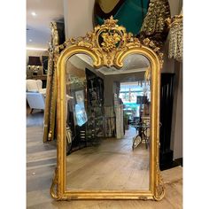 an ornate gold framed mirror sitting on top of a wooden floor