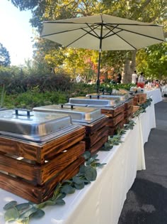 an outdoor buffet set up with wooden boxes and silverware on it's tables