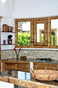 a large kitchen with wooden cabinets and marble counter tops in front of two open windows