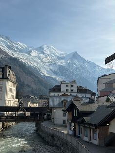 the mountains are covered in snow and there is a river running through it with buildings on both sides