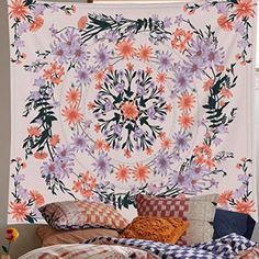 an image of a flower tapestry hanging on the wall above a bed with pillows and blankets