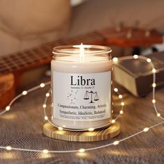 a lit candle sitting on top of a wooden table next to a string of lights