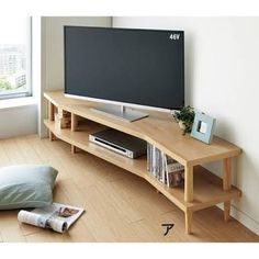 a flat screen tv sitting on top of a wooden entertainment center next to a window